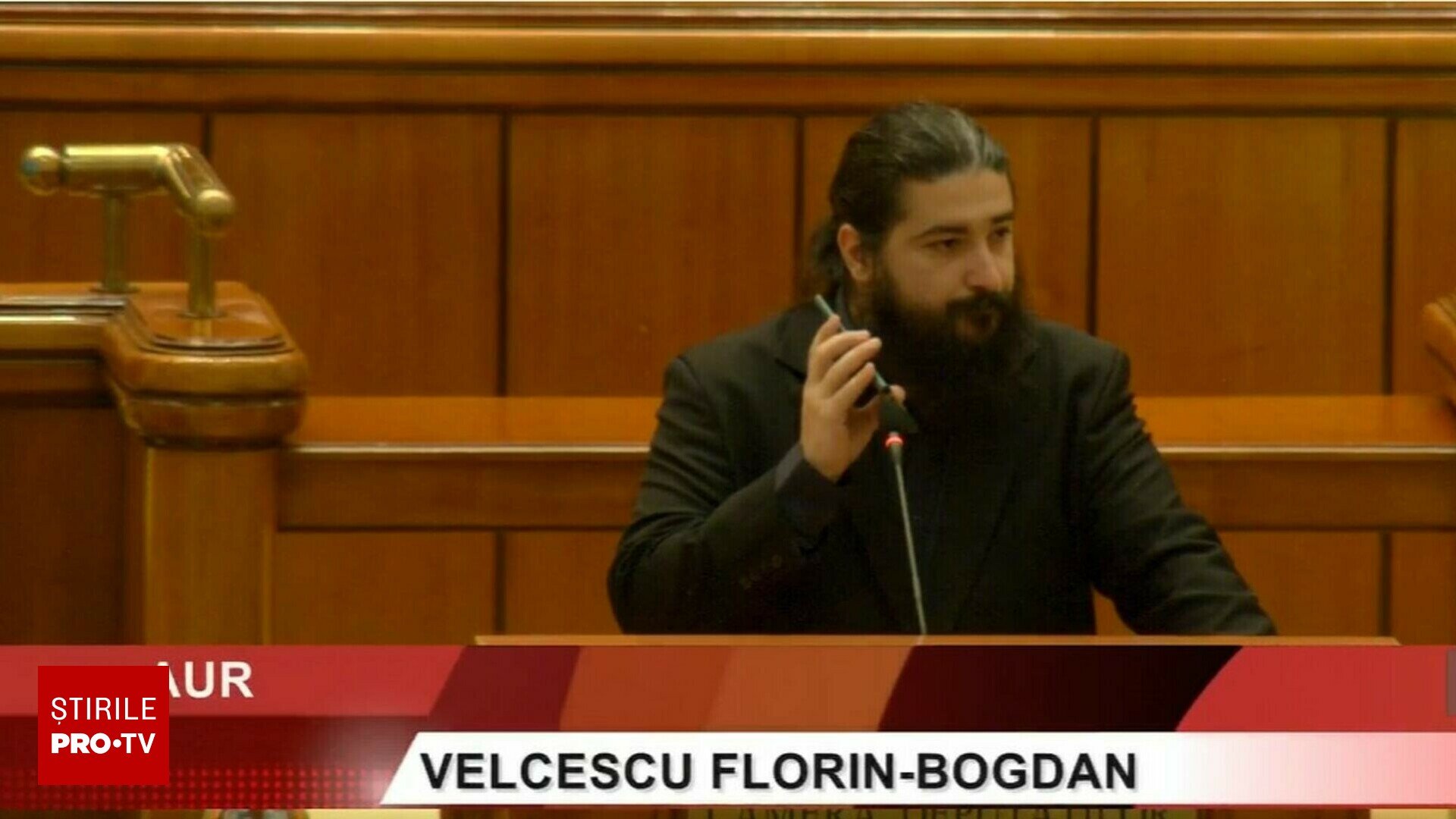 Următoarea reformulare a titlului poate fi utilizată: „Dezordine în Parlamentul României pe tema Legii împotriva extremismului: un deputat AUR difuzează muzică rap la microfon, exclamând ‘Să vă fie rușine'”